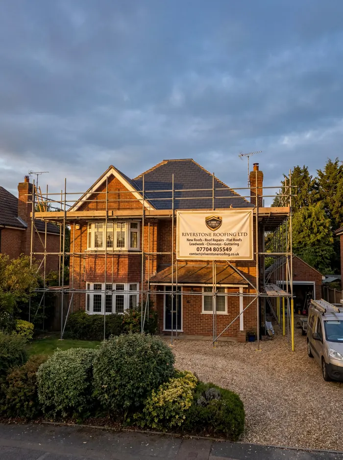 A house undergoing a Riverstone Roofing project with a branded banner on the scaffolding